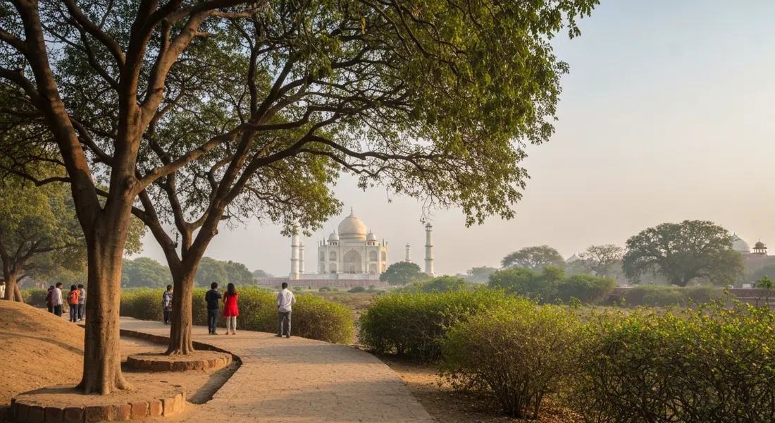 un sendero sombreado dentro de Taj Nature Walk, matorral y montículos con vistas con el Taj Mahal apenas visible sobre los árboles en la luz suave de la mañana
